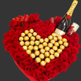 Heart-shaped rose arrangement with chocolates and champagne bottles