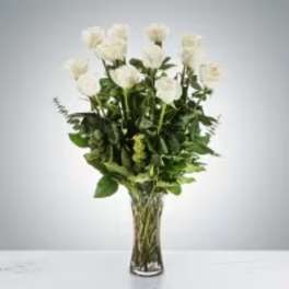 White flowers in a tall glass vase with green foliage