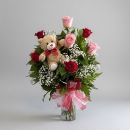 Bouquet of pink and red roses with a teddy bear in a glass vase