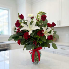 Bouquet of red roses and white lilies in a glass vase with a red ribbon