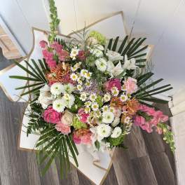 Mixed bouquet of pink, white, and green flowers wrapped in white paper