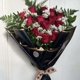 Bouquet of red roses with white filler flowers wrapped in black paper