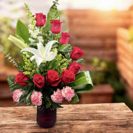 Red roses and white lilies in a dark glass vase