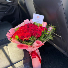 Bouquet of red roses wrapped in pink paper with a red ribbon
