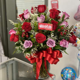 Bouquet of red and lavender roses in a glass vase with a red ribbon