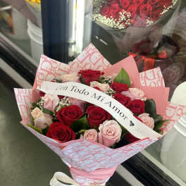 Bouquet of red and pink roses with a ribbon reading "Con Todo Mi Amor"