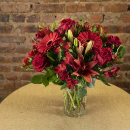 Red mixed flower bouquet in a clear glass vase