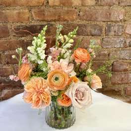 Peach and blush floral arrangement in a clear glass vase