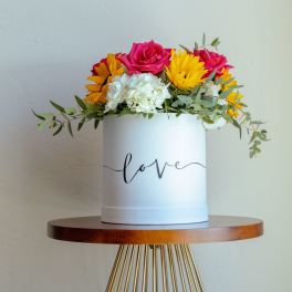 Round box arrangement with pink roses, yellow daisies, and white hydrangeas
