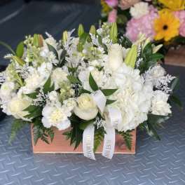 White floral arrangement in a wooden box with ribbon