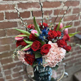 Bouquet of red roses, pink tulips, and pale hydrangea in a vase