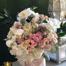 Pink and white floral arrangement in a round pink box with pearl trim