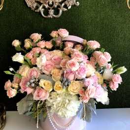 Pink and cream rose arrangement in a round pink box with pearl strands