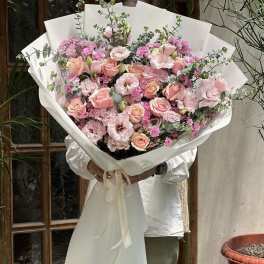 Large bouquet of pink roses and lisianthus with eucalyptus in white wrap