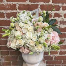 Cream and blush floral arrangement in a white ribbed vase