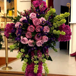 Tall standing floral spray with pink roses, purple flowers, and green accents