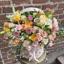 Mixed bouquet of roses and pink daisies in a round hatbox