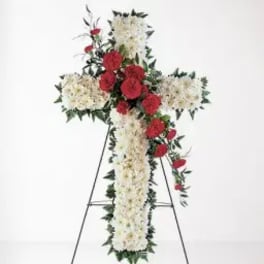 Standing floral cross with white flowers and red roses on an easel