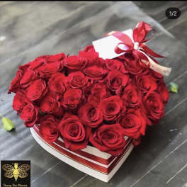 Heart-shaped box filled with red roses and a red ribbon bow