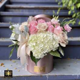 Pink and cream roses with white hydrangea in a pink hatbox