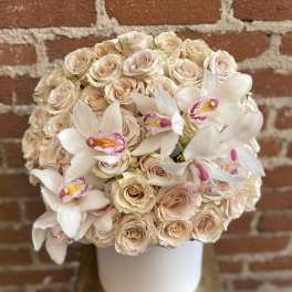 Cream roses and white orchids arranged in a white hat box
