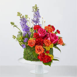 Colorful floral arrangement with roses, carnations, and tall purple blooms on a pedestal