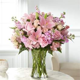 Pink lilies and roses arranged in a clear glass vase