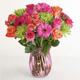 Mixed pink and orange flowers in a pink glass vase