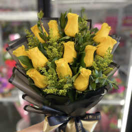 Bouquet of yellow roses wrapped in black paper with a ribbon