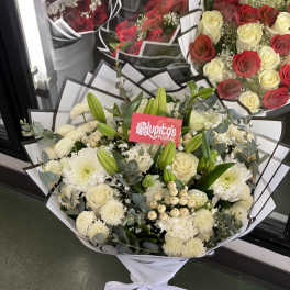White bouquet with roses, chrysanthemums, and lilies wrapped in paper