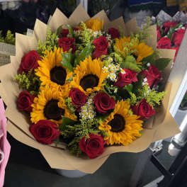 Bouquet of red roses and yellow sunflowers wrapped in tan paper