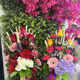 Two colorful floral arrangements in patterned vases with ribbons