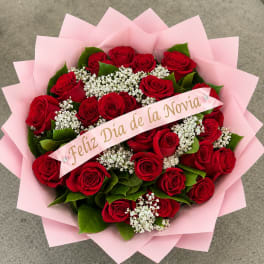 Bouquet of red roses with white filler flowers wrapped in pink paper