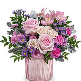 Pink and purple mixed flower arrangement in a pink glass vase