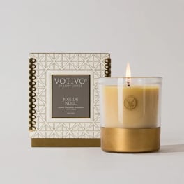 Lit holiday candle in a glass jar beside its decorative box