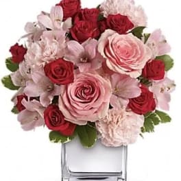 Pink and red rose bouquet in a clear square vase