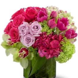 Pink and lavender roses with tulips in a glass vase