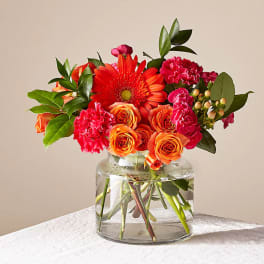 Orange and pink flowers arranged in a clear glass vase