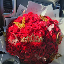 Large bouquet of red roses with decorative butterfly picks and a crown topper