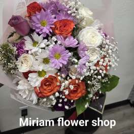 Mixed bouquet of roses and daisies wrapped in pale pink paper