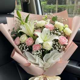 Bouquet of pink and white roses with white lilies wrapped in pink paper