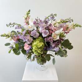 Pastel bouquet of roses, hydrangea, and orchids in a glass vase