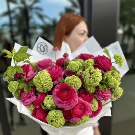 Bouquet of hot pink roses and green pom-pom blooms wrapped in white paper