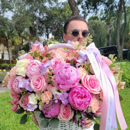 Large basket of pink and lavender flowers with ribbon