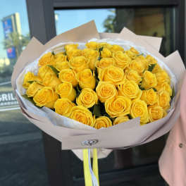 Bouquet of yellow roses wrapped in pale paper