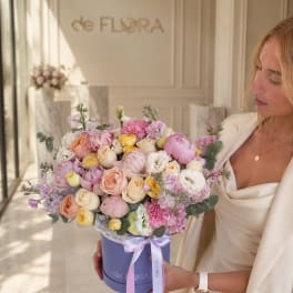 Woman holding a pastel mixed flower bouquet in a lavender hat box