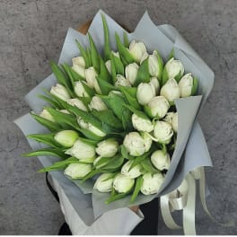 Bouquet of white tulips wrapped in gray paper