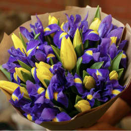 Bouquet of purple irises and yellow tulips wrapped in brown paper