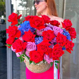 Large bouquet of red roses and blue hydrangeas in a woven basket