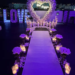 Purple floral wedding aisle with heart arch, candles, and lit LOVE sign